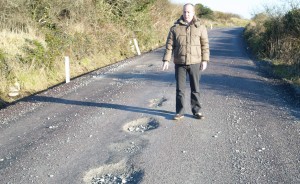 Councillor Jim Daly inspects some of the potholes.